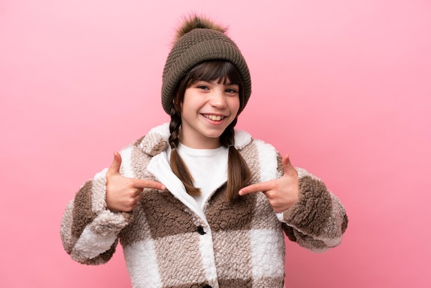 Little caucasian girl with winter jacket isolated on pink background proud and selfsatisfied