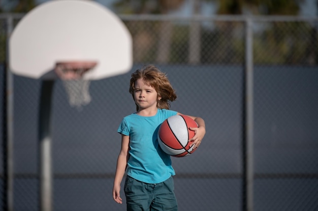 Little caucasian sports kid playing basketball holding ball