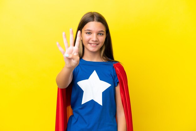 Little caucasian superhero girl isolated on yellow background happy and counting four with fingers