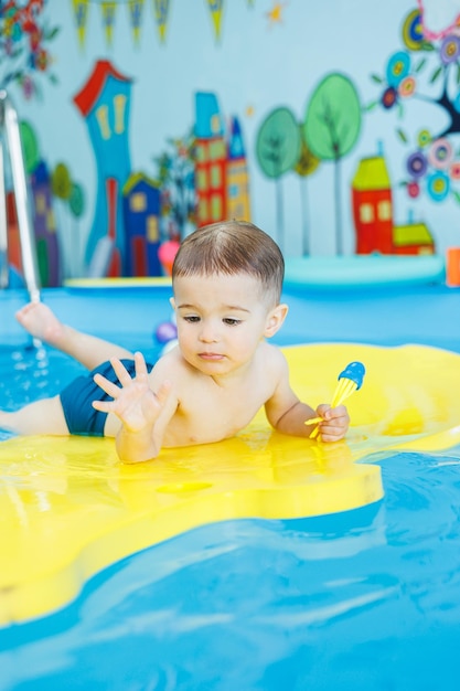 Little cheerful 2yearold boy is learning to swim in the pool Swimming lessons for children Swimming school for children