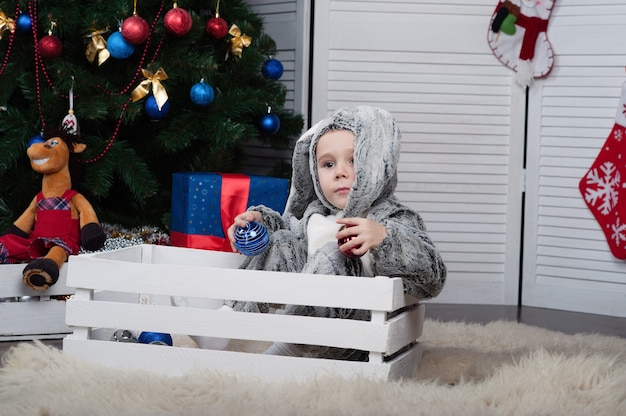 little cheerful boy in a New Years bunny costume with new year tree