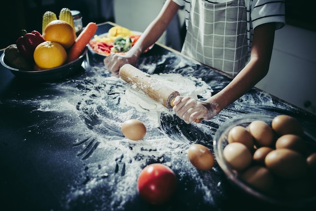 Little chef using rolling pin stretching the dough Cooking concept