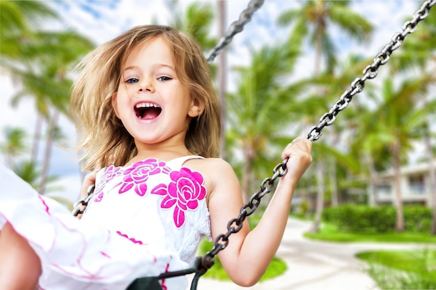 Little child blond girl having fun on a swing