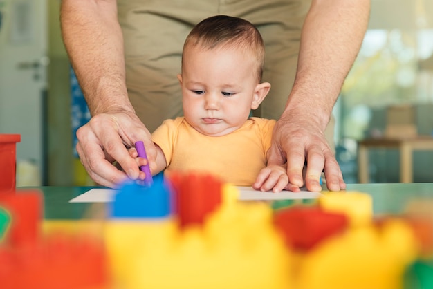 Little child and father are drawing on a paper. Kindergarten concept.