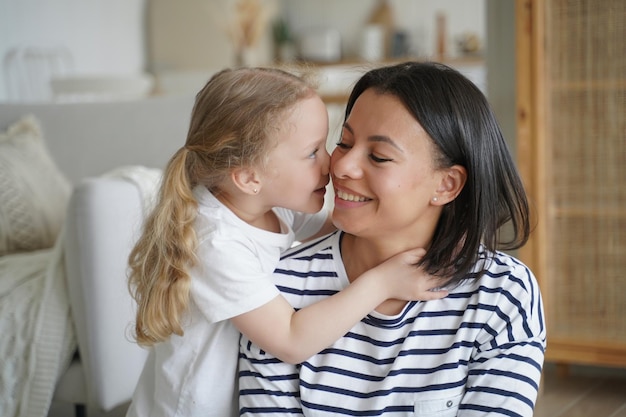 Little child girl adopted daughter hugs mom touching nose to mother's cheek Happy adoption concept