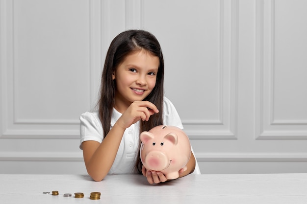 Little child girl with piggy bank at home