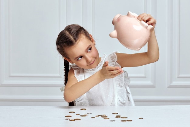 Little child girl with piggy bank at home