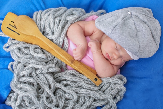 A little child in a grey cap lies with a spoon