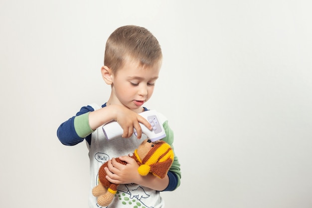 Little child playind doctor measure temperature for toy bear