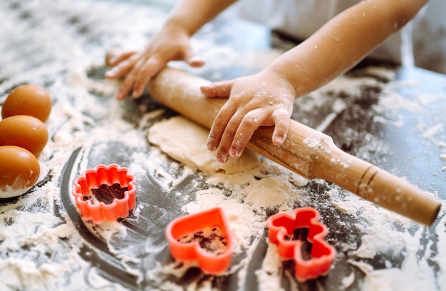 Little child preparing dough for baking. Small hands kneading dough and rolled dough.