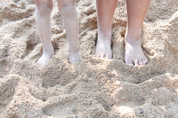 Little child's legs in the sand on the beach