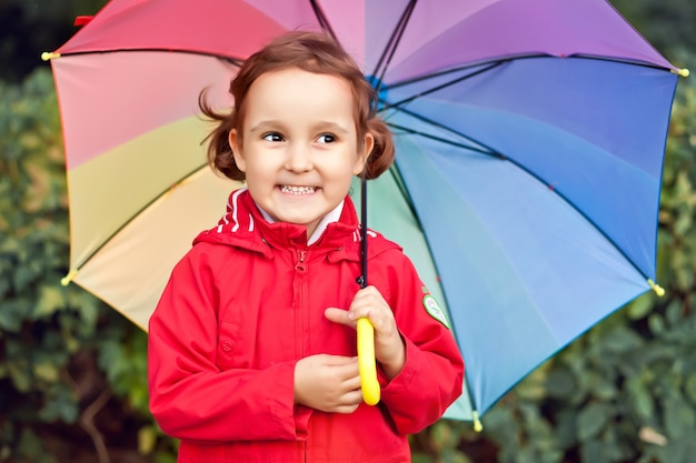 Little child with multicolored rainbow umbrella outdoors.