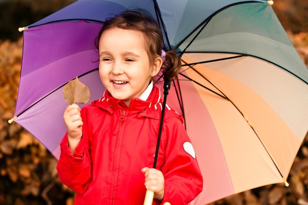 Little child with multicolored rainbow umbrella outdoors