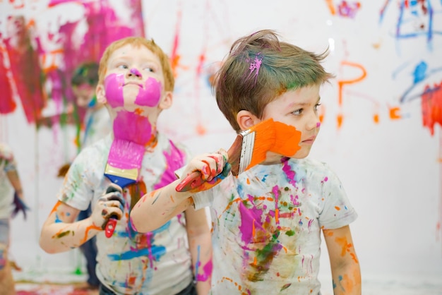 Little children have fun and draw bright colors on their faces high quality photo