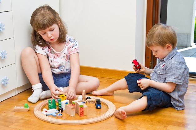 Little Children playing with wooden train in the room