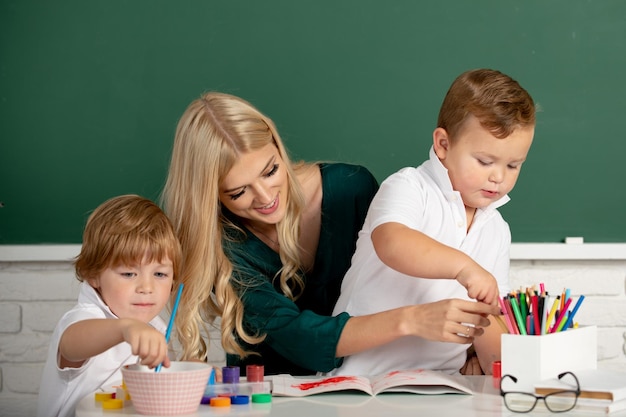 Little children with kindergarten teacher drawing at table indoors learning and playing teacher tuto