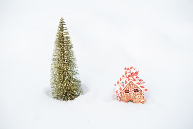 Little Christmas tree and gingerbread house in snow outdoor. Merry christmas. happy new year. High quality photo