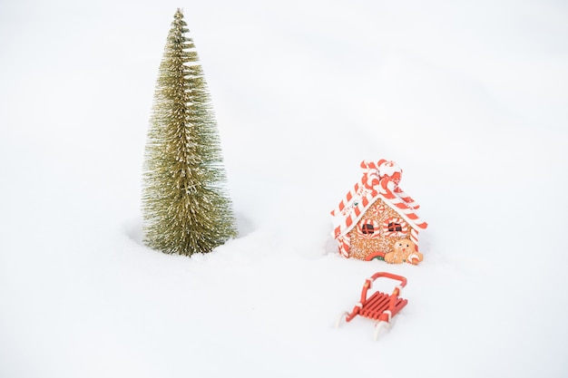 Little Christmas tree, sleigh and gingerbread house in snow outdoor. Merry christmas. happy new year. High quality photo