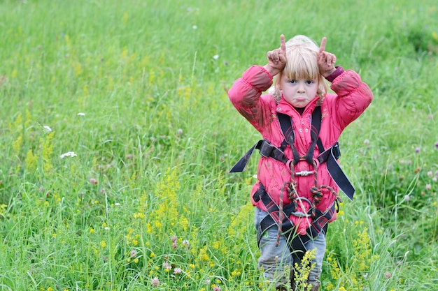 Little climber girl in a red jacket in nature