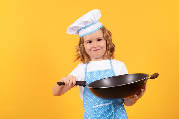 Little cook with cooking pan Chef kid boy making healthy food Portrait of little child in chef hat isolated on studio background Child chef Cooking process