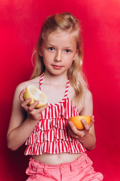 Little cute adorable girl with fruits on red background