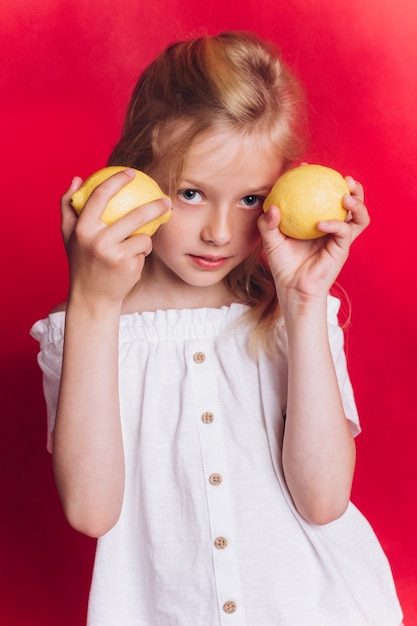 Little cute adorable girl with fruits on red background