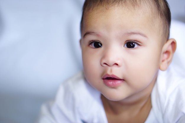 Little cute asian baby happily lying down on the blue bed sheet the concept of empathy adorable