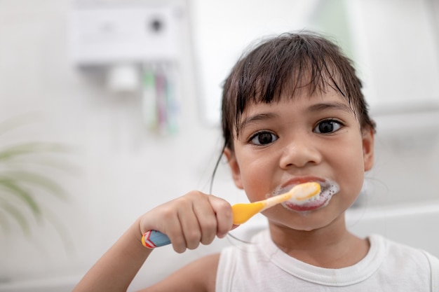 Little cute baby girl cleaning her teeth with a toothbrush in the bathroom