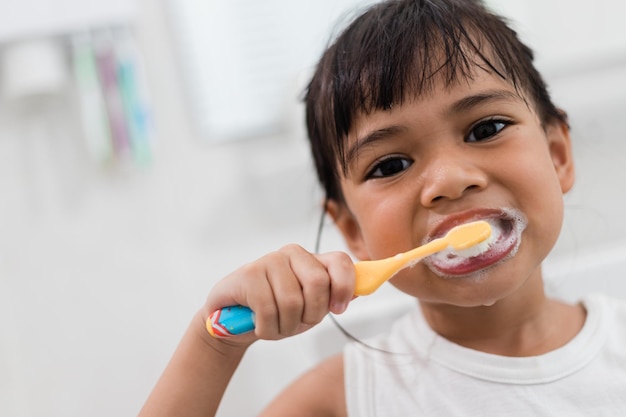 Little cute baby girl cleaning her teeth with a toothbrush in the bathroom