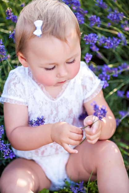 Little cute baby girl sitting in a lavender field in summer park