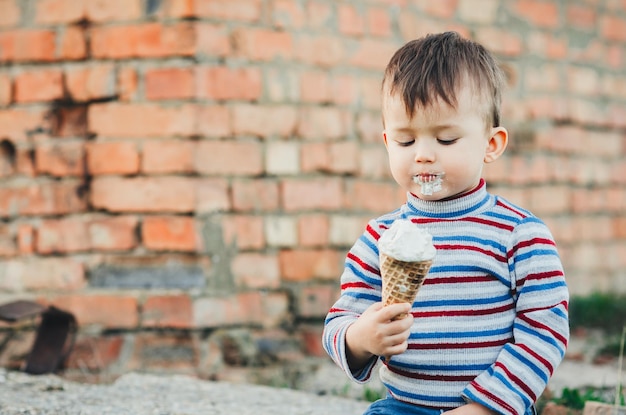 little cute boy eating ice cream three years very appetizing amid nature green grass