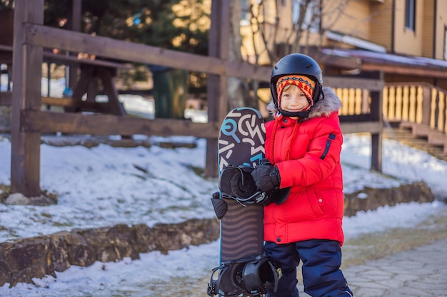 Little cute boy is ready for snowboarding activities for children in winter childrens winter sport