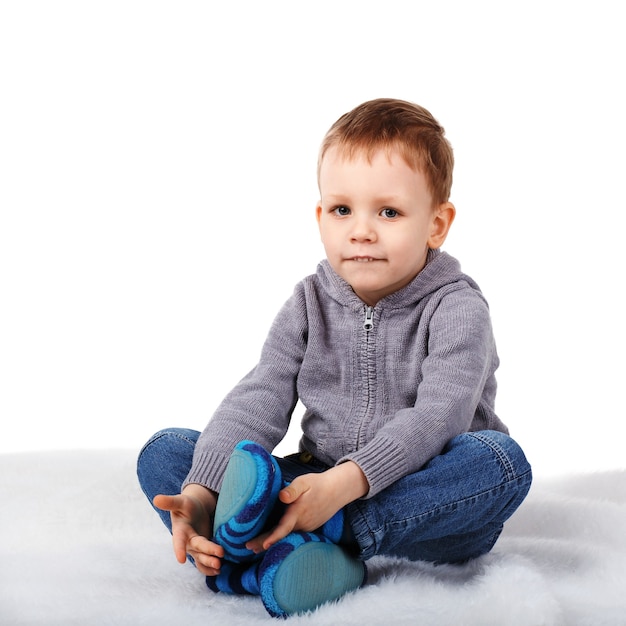 Little cute boy sitting on the floor biting her lower lip isolated on white