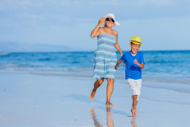 Little cute boy with his mother having fun at the white sand beach