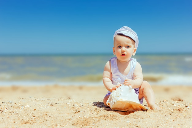 Little cute boy with seashell in hands at beach