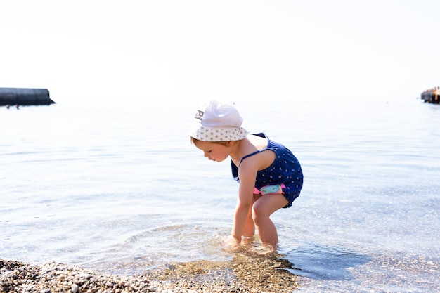 Little cute child girl playing on the seashore in summer