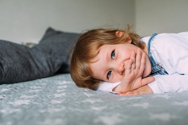 Little cute child is lying and having fun at home on sofa smiling and laughing