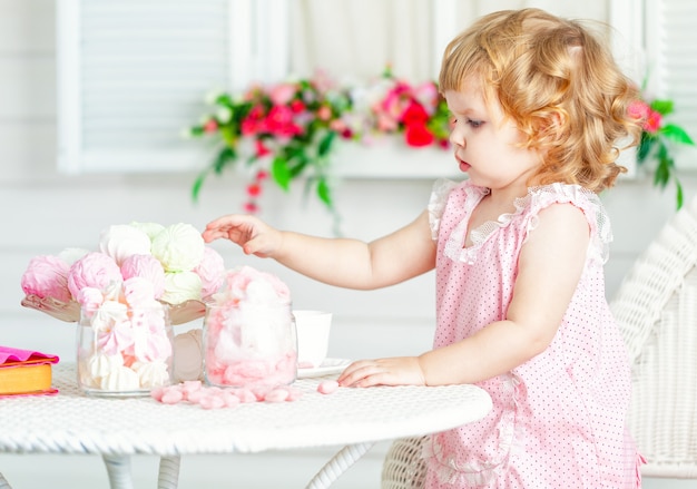 Little cute curly girl in a pink dress with lace and polka dots 