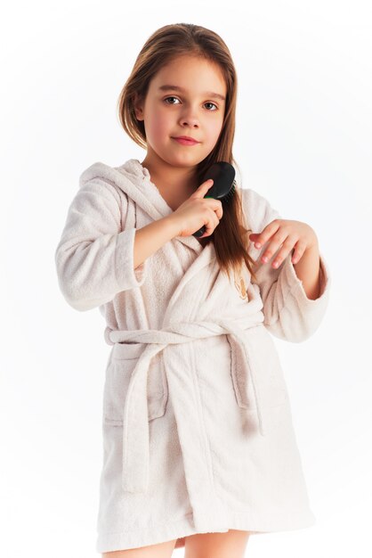 Little cute girl in a bathrobe combing hair