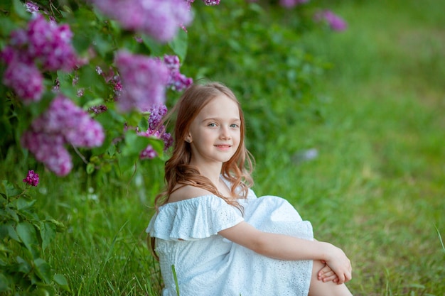 Little cute girl in a blooming lilac in spring