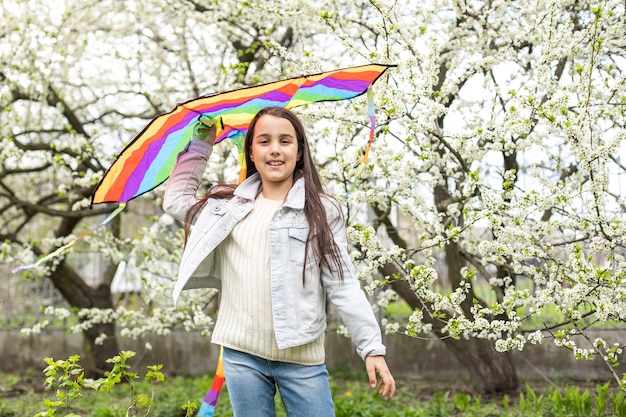 little cute girl flying a rainbow kite.