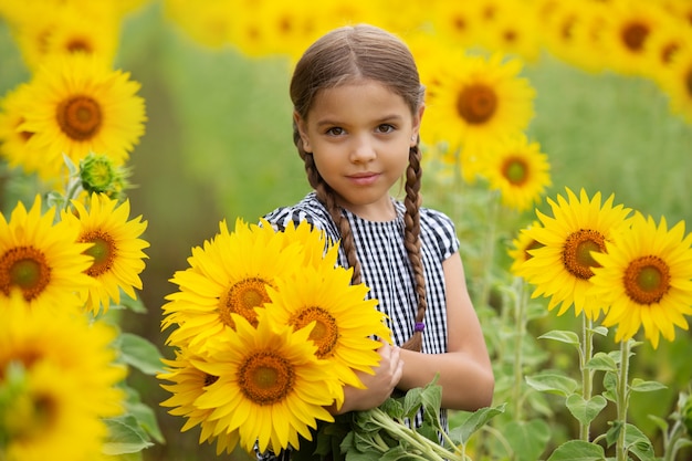 Little cute girl holding sunflowers