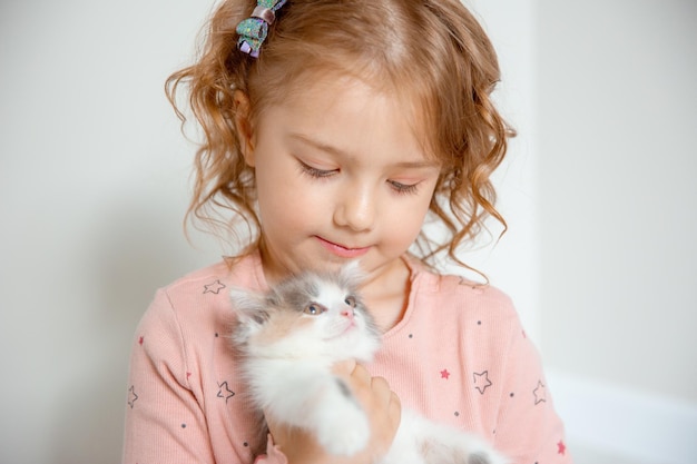 a little cute girl holds a kitten hugs