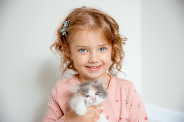 a little cute girl holds a kitten hugs