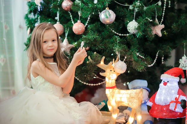 Little cute girl near christmas tree. Children under Christmas tree with gift boxes.