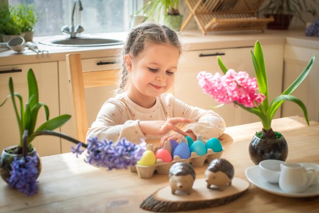 A little cute girl paints Easter eggs spring flowers hyacinths colorful eggs holiday decoration