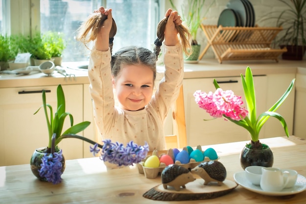 A little cute girl paints Easter eggs spring flowers hyacinths colorful eggs holiday decoration