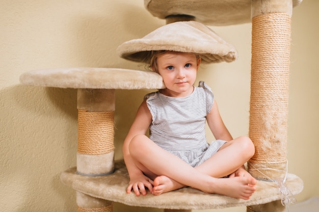 Little cute girl plays with a sore cat house.