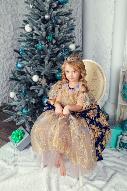 Little cute girl in princess dress near the New Year tree, beautiful Christmas decor