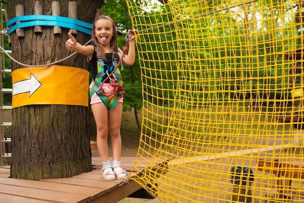 Little cute girl runs an obstacle course in a rope park